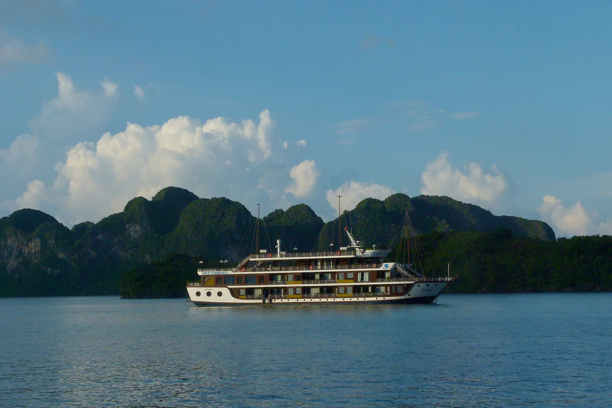 Navio de cruzeiro navegando entre as formações calcárias da Baía de Halong, Vietnã
