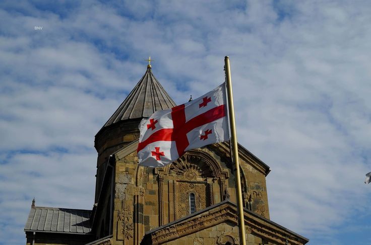 Bandeira da Geórgia diante de uma igreja de pedra
