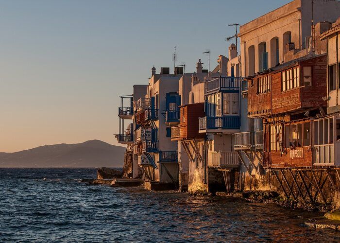 Mykonos ao entardecer, com casas brancas, moinhos e o mar Egeu