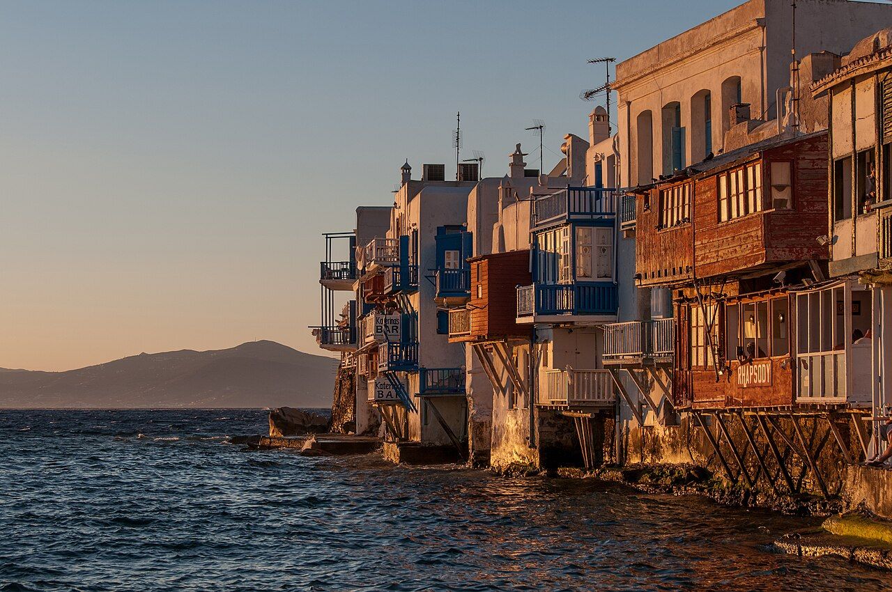 Mykonos ao entardecer, com casas brancas, moinhos e o mar Egeu