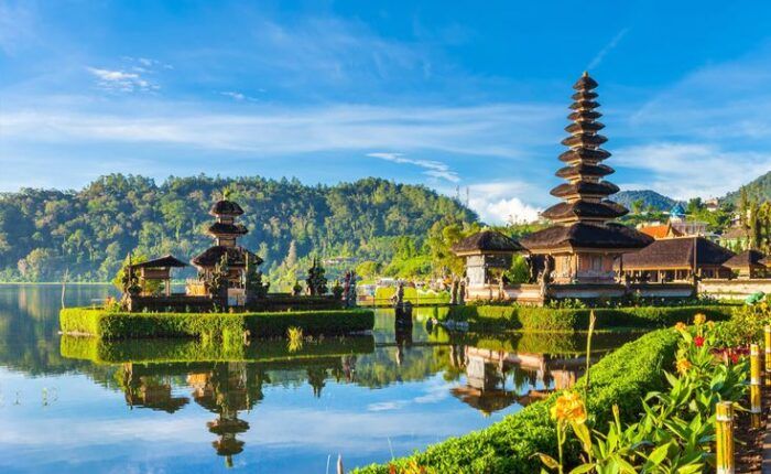 Templo à beira de um lago em Bali, com telhados em camadas refletidos na água.