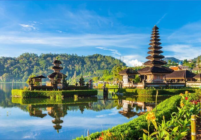 Templo à beira de um lago em Bali, com telhados em camadas refletidos na água.