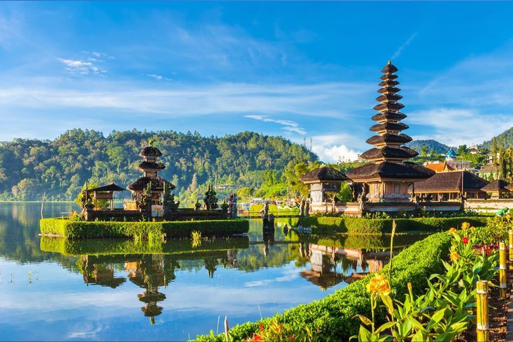 Templo à beira de um lago em Bali, com telhados em camadas refletidos na água.