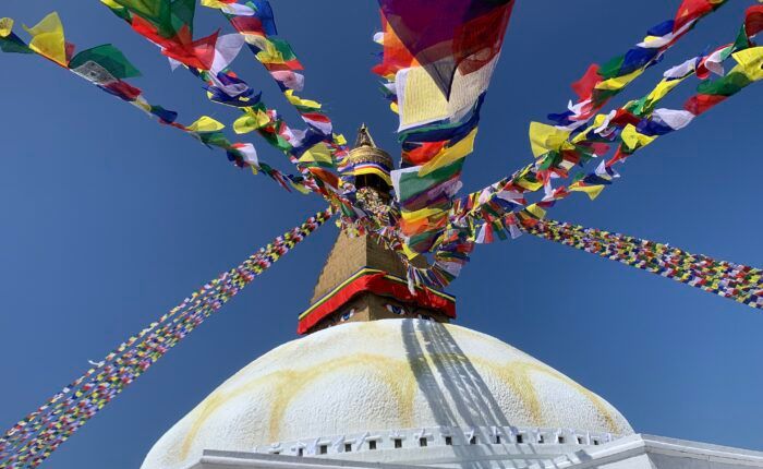 Cúpula branca da estupa de Boudhanath, em Kathmandu, sob bandeiras de oração coloridas