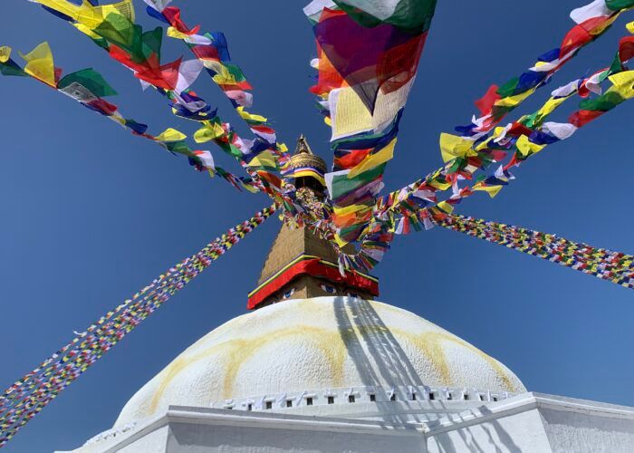 Cúpula branca da estupa de Boudhanath, em Kathmandu, sob bandeiras de oração coloridas