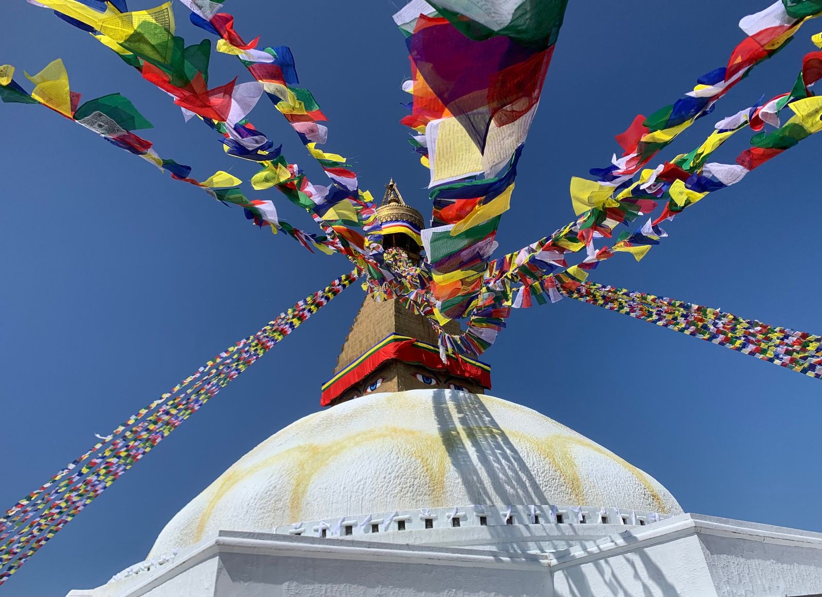 Cúpula branca da estupa de Boudhanath, em Kathmandu, sob bandeiras de oração coloridas