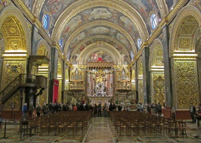 Nave da Co-Catedral de São João, em Valletta, com lápides de mármore colorido no piso e decoração dourada.