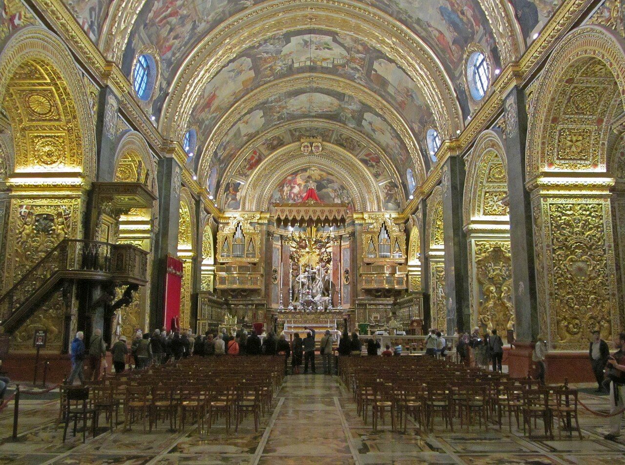 Nave da Co-Catedral de São João, em Valletta, com lápides de mármore colorido no piso e decoração dourada.