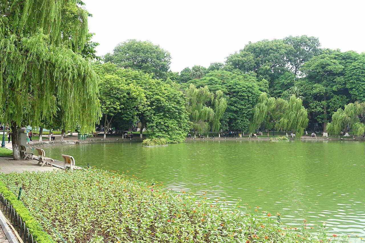 Lago Hoan Kiem com margens arborizadas e bancos de passeio em Hanói, Vietnã