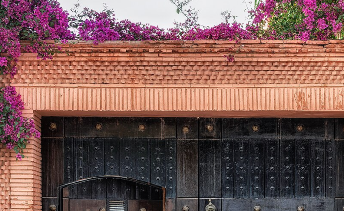 Portal em tons terrosos cercado por flores em Marrakech.