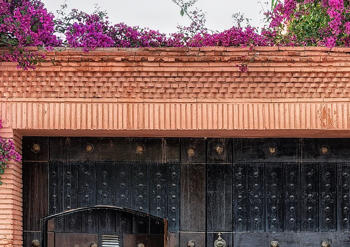 Portal em tons terrosos cercado por flores em Marrakech.