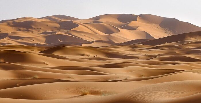 Dunas alaranjadas do deserto de Merzouga sob céu azul.