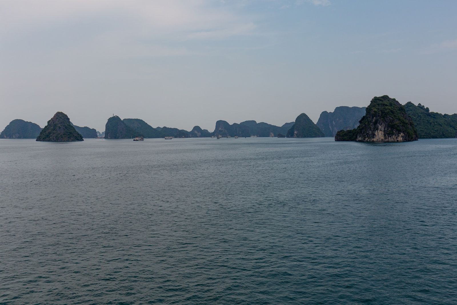 Formações calcárias e embarcações na baía de Ha Long, Vietnã