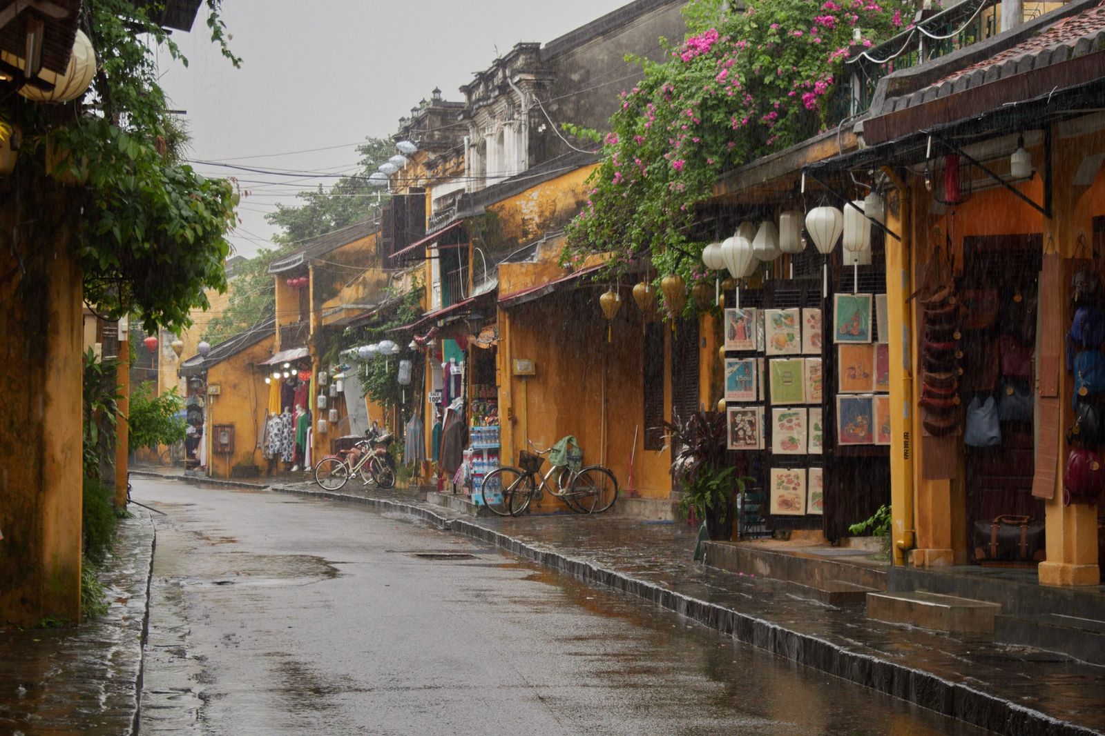 Rua molhada pela chuva, fachadas e lanternas no centro antigo de Hoi An, Vietnã