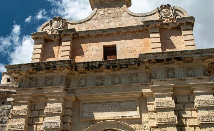 Porta monumental de Mdina, em Malta, com arco de entrada e decoração em pedra.
