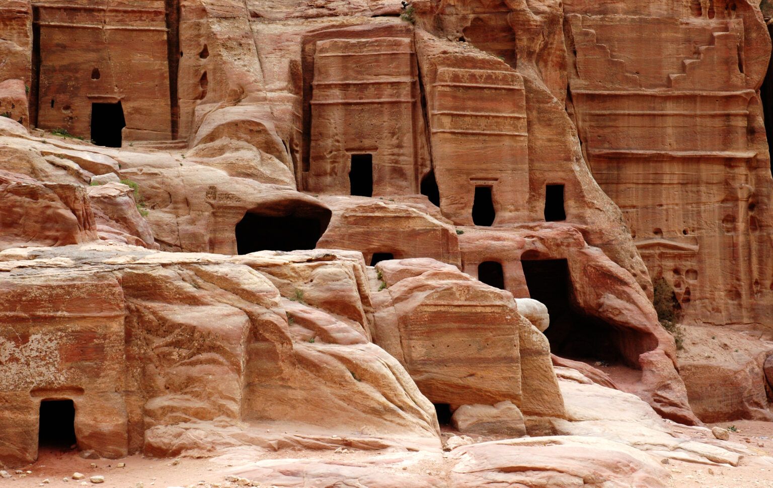 Conjunto de túmulos de Petra com fachadas entalhadas e entradas escuras na rocha avermelhada.