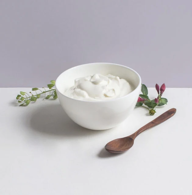 Tigela branca com skyr e uma colher sobre a mesa