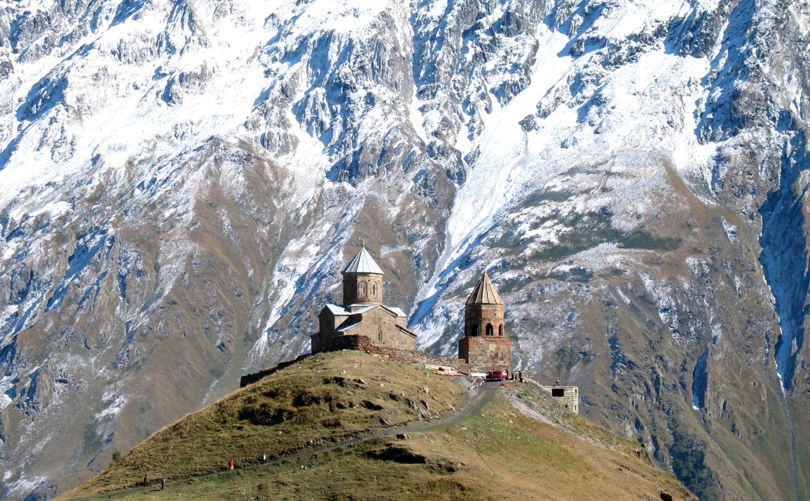 Igreja da Trindade de Gergeti e campanário sobre uma colina, diante de montanhas nevadas
