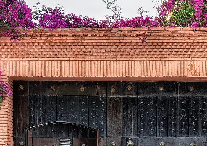 Portal em tons terrosos cercado por flores em Marrakech.